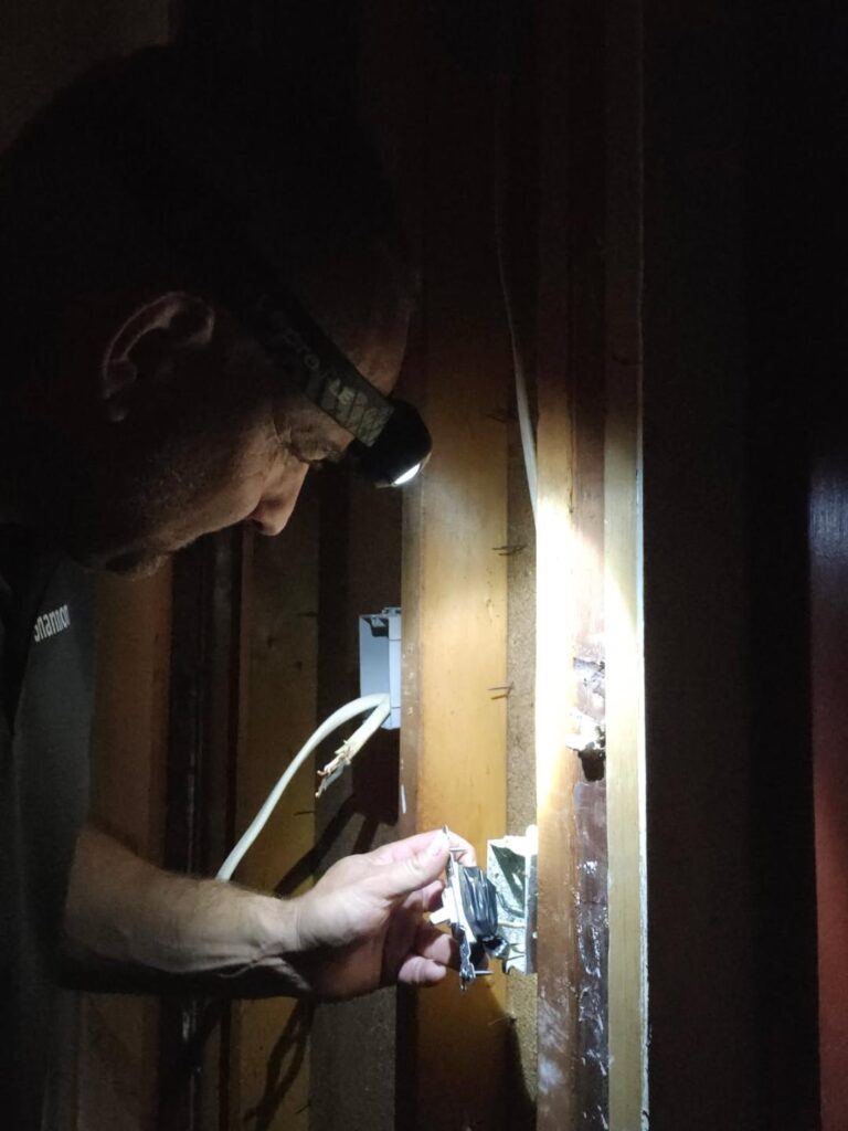 Electrician troubleshooting an outlet not working behind an open wall in a Northwest Arkansas home