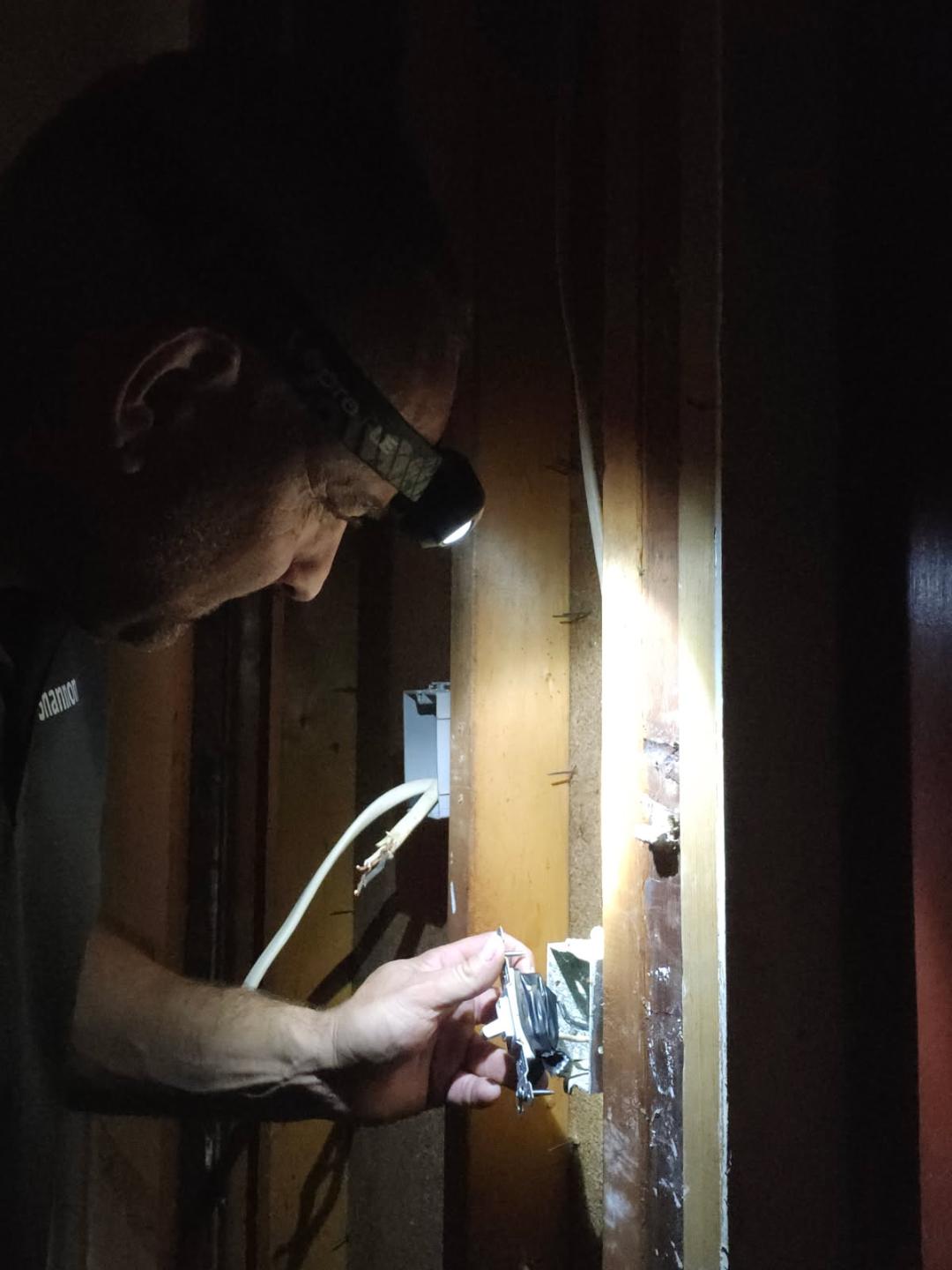 Electrician troubleshooting an outlet not working behind an open wall in a Northwest Arkansas home