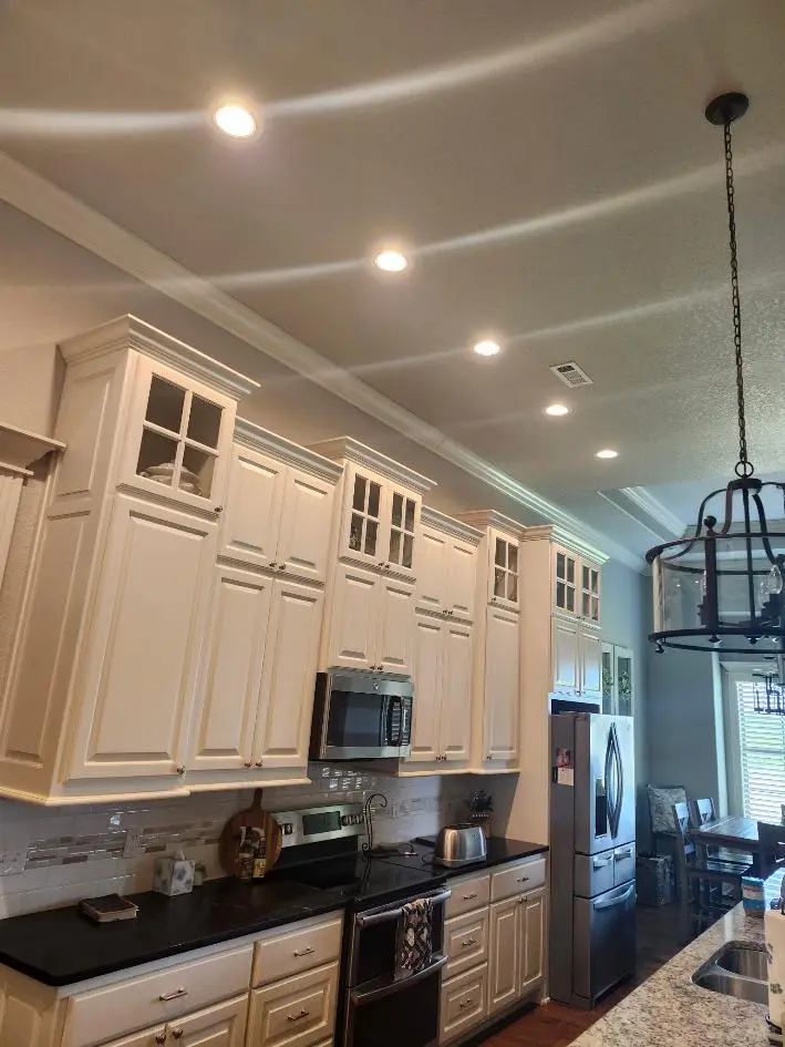 Recessed ceiling lights illuminating a kitchen with white cabinets